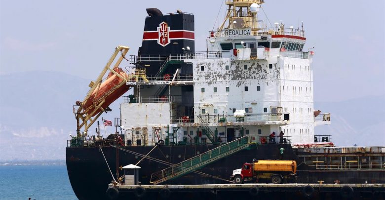 In this April 16 2019 photo a ship fills up on fuel from a tanker truck on the Thor terminal in Carrefour a district of Port au Prince Haiti.